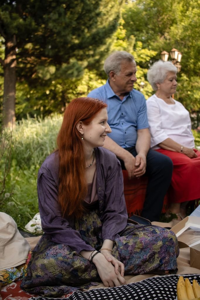 Outdoor family gathering in Tomsk, featuring a smiling redhead woman with her grandparents.